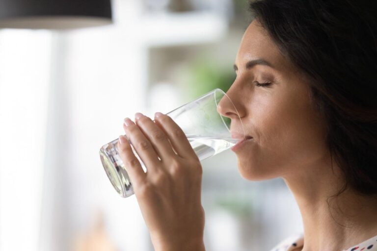 a woman enjoys a glass of water in detox