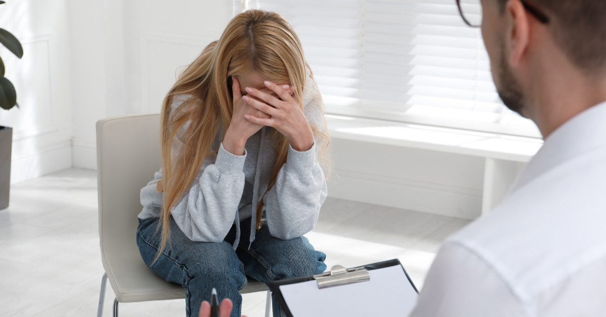 A woman speaking to a therapist with her head in her hands in meth addiction treatment